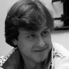 Zbliżenie na twarz mężczyzny w białej kurtce z ćwiekami, przypominającego postać z filmu "Tulipan".