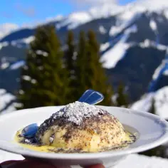 Austriackie knedle z makiem i sosem waniliowym, pyszność, z której słynie Austria, na tle ośnieżonych gór.