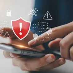 Dłonie trzymające smartfon, nad którym wyświetlają się ikony bezpieczeństwa: tarcza z wykrzyknikiem, kłódka, wirus. To symbol ochrony przed zagrożeniami, czyli antywirus na telefon.