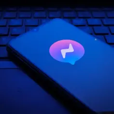 Smartfon z logo Messenger na klawiaturze komputera.