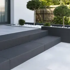 Nowoczesne schody betonowe zewnętrzne z antracytowymi stopniami i jasną płytą tarasową. Idealne, by wykończyć schody betonowe wewnętrzne.