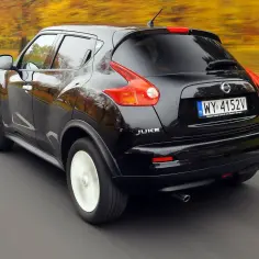 Czarny Nissan Juke 1.6 benzyna w ruchu, jesienny krajobraz w tle.