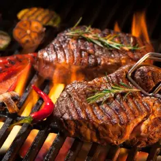 Pyszny stek z grilla, skwierczący na ogniu, z dodatkiem pieczonej papryki, czosnku i chili.