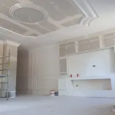 Elegancka sztukateria z ledami zdobi sufit i ściany, tworząc nowoczesne wnętrze w trakcie remontu.
