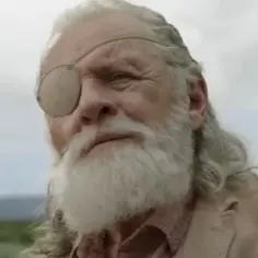 Anthony Hopkins w filmach, jako starszy mężczyzna z siwą brodą i opaską na oku, wpatruje się w dal.