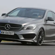 Szary Mercedes CLA 180 na drodze, z kierowcą w okularach przeciwsłonecznych za kierownicą.