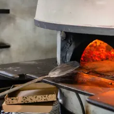 Piec do pizzy z rozżarzonymi węglami. Łopatka czeka, by włożyć do środka kolejne pyszne pizze.