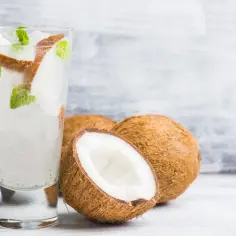 Orzeźwiający drink z malibu z mlekiem kokosowym, lodem i miętą, otoczony świeżymi kokosami.