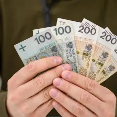 Ręce trzymają polskie banknoty: 100 zł i 200 zł. Od kiedy 800 plus, takie widoki stają się częstsze.