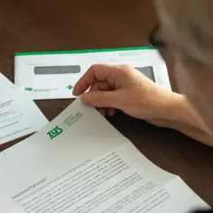 Osoba czyta dokument ZUS. Może to być informacja o zwrocie nadpłaty lub inne pismo z ubezpieczalni.