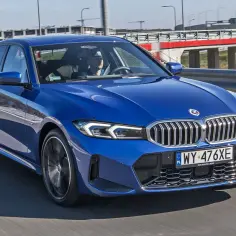Niebieskie BMW 320 jedzie po drodze, za kierownicą siedzi mężczyzna.