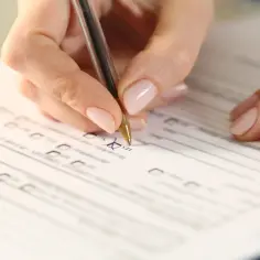 Dłoń wypełnia formularz, zaznaczając "TAK" w rubryce wniosku o wydanie orzeczenia o stopniu niepełnosprawności.