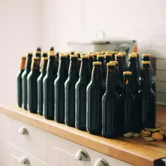 Rząd ciemnych butelek piwa craftowego stoi na blacie. Zastanawiasz się, jak przechowywać piwo craftowe w pionie czy w poziomie?