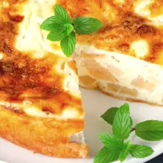 Puszyste ciasto z serka wiejskiego z kawałkami owoców, ozdobione listkami mięty. Idealne na deser.