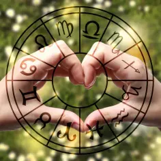 Dłonie tworzą serce w kole zodiaku, gdzie Ryby i Lew są obok siebie.
