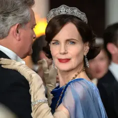 Elegancka kobieta w tiarze i błękitnej sukni, z dłonią na ramieniu mężczyzny w garniturze. To część obsady Downton Abbey.