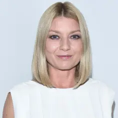 Uśmiechnięta Edyta Olszówka w białej sukience. Wiele osób zastanawia się, ile lat ma Edyta Olszówka, ale jej wiek nie wpływa na jej urok.