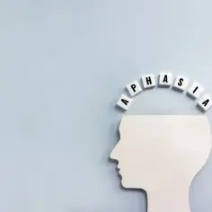 Biały profil głowy z literami tworzącymi łuk nad nim. Litery układają się w napis "Aphasia", symbolizując trudności w komunikacji, jak w przypadku afazji ruchowej.