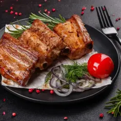 Soczyste żeberka z piekarnika, idealne na obiad. Podane z pomidorkiem, cebulą i rozmarynem.