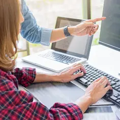 Dwóch programistów pracuje nad kodem, jeden wskazuje na ekran monitora z kodem, który może być związany z DirectX 12.
