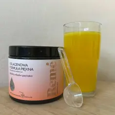 Remé Kolagenowa Formuła Piękna w proszku o smaku pomarańczy i marakui, obok szklanki z żółtym napojem i miarki.