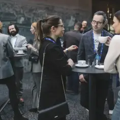 Ludzie rozmawiają przy stolikach, pijąc kawę. To właśnie networking – budowanie relacji zawodowych.