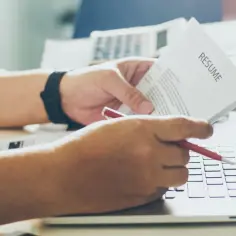 Osoba przegląda CV na laptopie, zastanawiając się, czy kłamstwo w CV lub naciąganie doświadczenia zawodowego się opłaca.