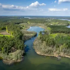 Malownicze pojezierze brodnickie z lotu ptaka: lasy, jeziora i błękitne niebo z chmurami.