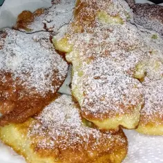 Puszyste racuchy z jabłkami na kefirze i sodzie, posypane cukrem pudrem, wyglądają apetycznie.