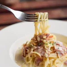 Widok spaghetti carbonara z chrupiącym guanciale. To właśnie guanciale co to jest, sekretny składnik tej potrawy.