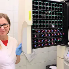 Uśmiechnięta laborantka w niebieskich rękawiczkach obok urządzenia do analizy próbek. To przyszłość po mikrobiologii, gdzie precyzja spotyka się z technologią.