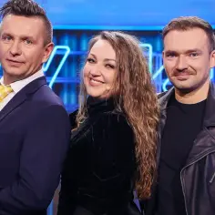 Trójka artystów z kabaretu Jurki: mężczyzna w garniturze i żółtym krawacie, uśmiechnięta kobieta w czarnym welurowym golfie i mężczyzna w skórzanej kurtce.