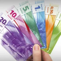 Dłoń trzyma kolorowe banknoty z napisem "txantxi", lokalną walutą w Hiszpanii.