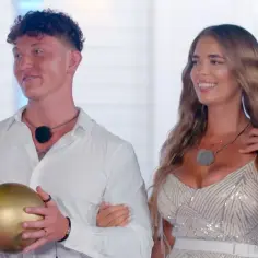 Para z Hotel Paradise 7, on trzyma złotą kulę, ona w błyszczącej sukience.