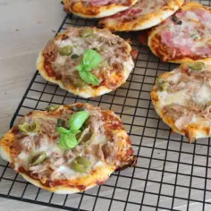 Mini pizze z tuńczykiem, oliwkami i bazylią na kratce.