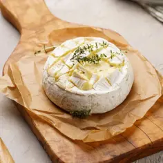 Zapiekany ser camembert z ziołami na desce. Czy ser camembert jest zdrowy? W umiarkowanych ilościach może być częścią zbilansowanej diety.