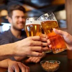 Trzech przyjaciół wznosi toast piwem, zastanawiając się, ile etanolu jest w piwie.