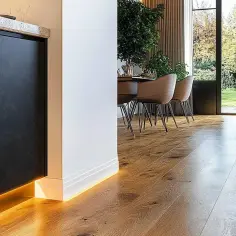 Nowoczesne wnętrze z drewnianą podłogą i subtelnym oświetleniem LED. Eleganckie rozwiązanie co zamiast listew przypodłogowych.