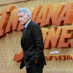 Harrison Ford, legendarny filmowy archeolog, pozuje przed napisem "Indiana Jones and the Dial of Destiny".