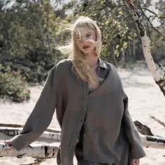 Kobieta w lnianym ubraniu na plaży. Zastanów się nad skutkami kupowania ubrań fast-fashion dla środowiska i portfela.