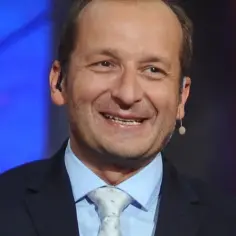 Uśmiechnięty Robert Górski z Kabaretu Moralnego Niepokoju w garniturze i jasnym krawacie.