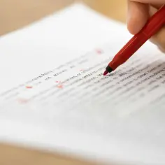 Poprawianie tekstu, jak przenieść spójniki w Wordzie. Czerwony długopis zaznacza błędy na dokumencie.