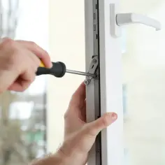 Regulacja drzwi balkonowych uchylnych. Ręce majsterkowicza dokręcają śrubę w mechanizmie okna.