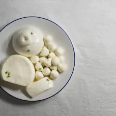 Różne rodzaje mozzarelli na talerzu. Czy mozzarella jest zdrowa? Tak, w umiarkowanych ilościach, dostarcza białka i wapnia.
