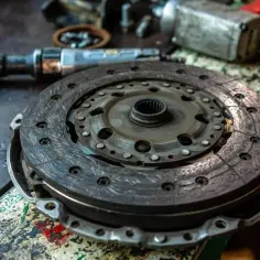 Zużyta tarcza sprzęgła, widoczna jej grubość. Obok narzędzia mechaniczne.
