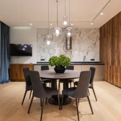 Nowoczesne wykończenie mieszkania pod klucz w Warszawie. Elegancka jadalnia z okrągłym stołem i designerskimi lampami.
