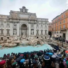 Tłum turystów z parasolami podziwia Fontannę di Trevi na Piazza di Trevi w Rzymie, Włochy.