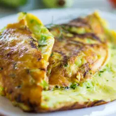Złocisty omlet z cukinią, delikatnie zrumieniony, podany na białym talerzu.