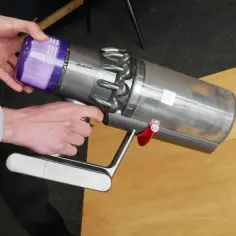 Ręce wyjmują fioletowy filtr z odkurzacza Dyson. Dowiedz się, jak wyczyścić filtr w Dyson Airwrap, aby urządzenie działało sprawnie.