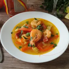 Aromatyczna zupa krewetkowa z kawałkami chorizo, marchewki i papryki, posypana świeżą natką pietruszki.